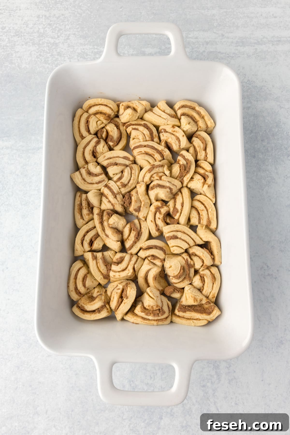 A casserole dish with cinnamon rolls sliced and fit into the dish in an even layer.