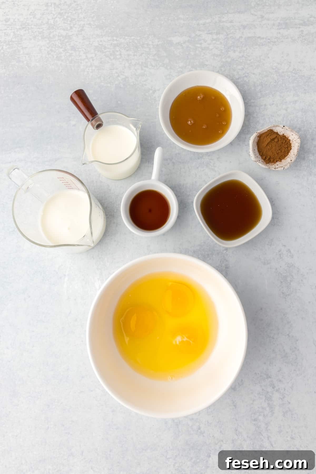 A bowl of whisked egg, with small cups and bowls of other ingredients on the table around it.
