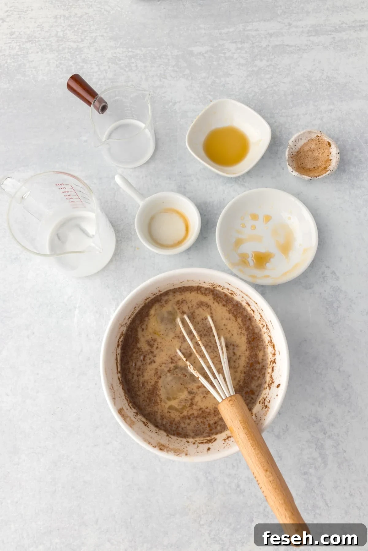 Whisking together ingredients in a bowl, with empty cups and bowls surrounding it.