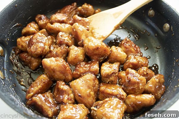 General Tso's Chicken in a black skillet with a wooden spoon.