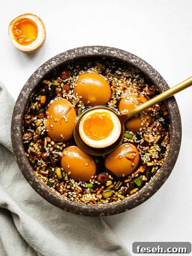 Mayak eggs in a ceramic bowl with one egg sliced in half to show the jammy egg centre.