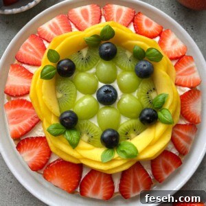 A plate topped with neatly arranged fresh fruit forms a colorful circular pattern.