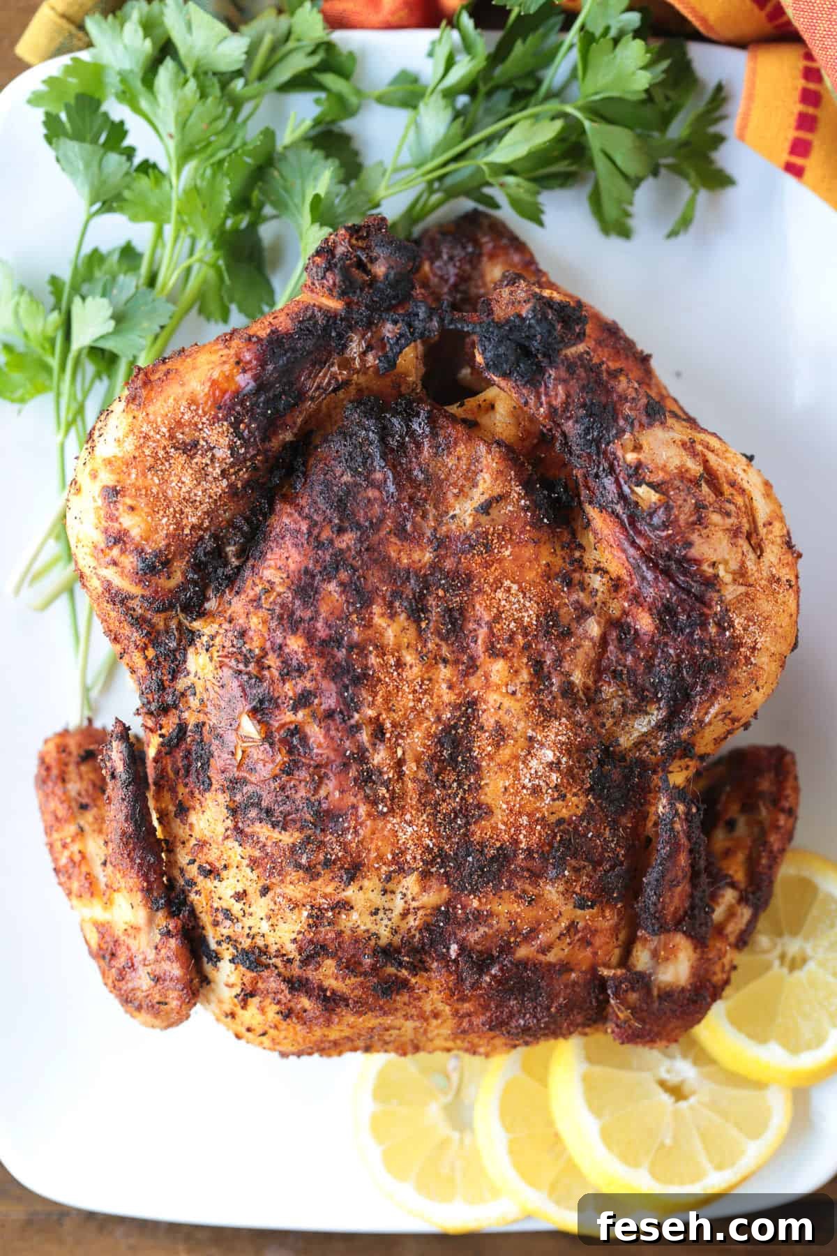 air fryer rotisserie chicken on a platter with lemons and parsley