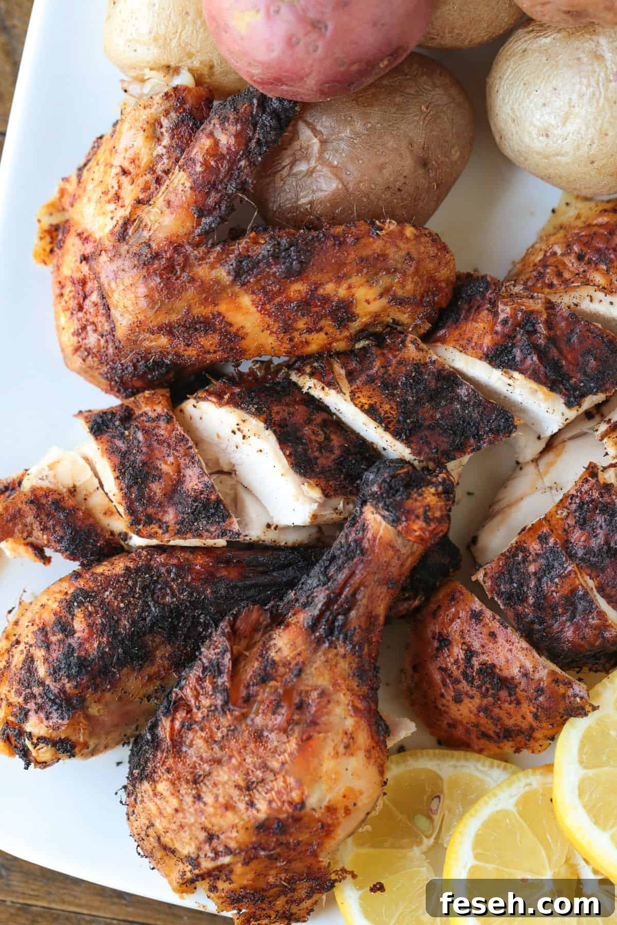 sliced chicken with skin on a platter with lemons