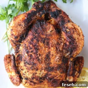 air fryer rotisserie chicken on a platter with lemons and parsley
