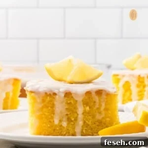 A slice of cake with white glaze and slice of lemon on top.