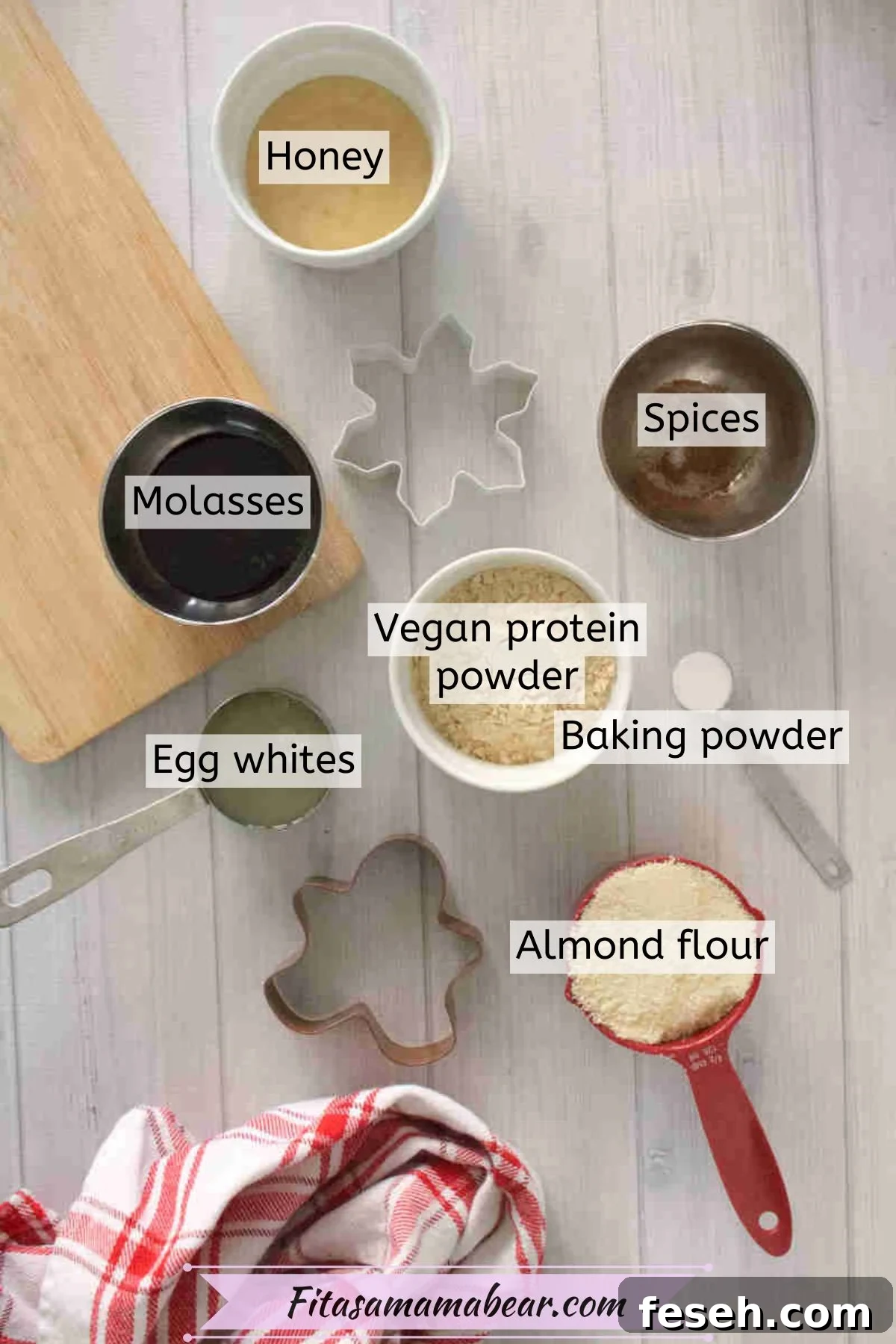 Multiple ingredients to make gingerbread cookies like protein powder, flour, and egg whites in measuring cups with text labels over top.