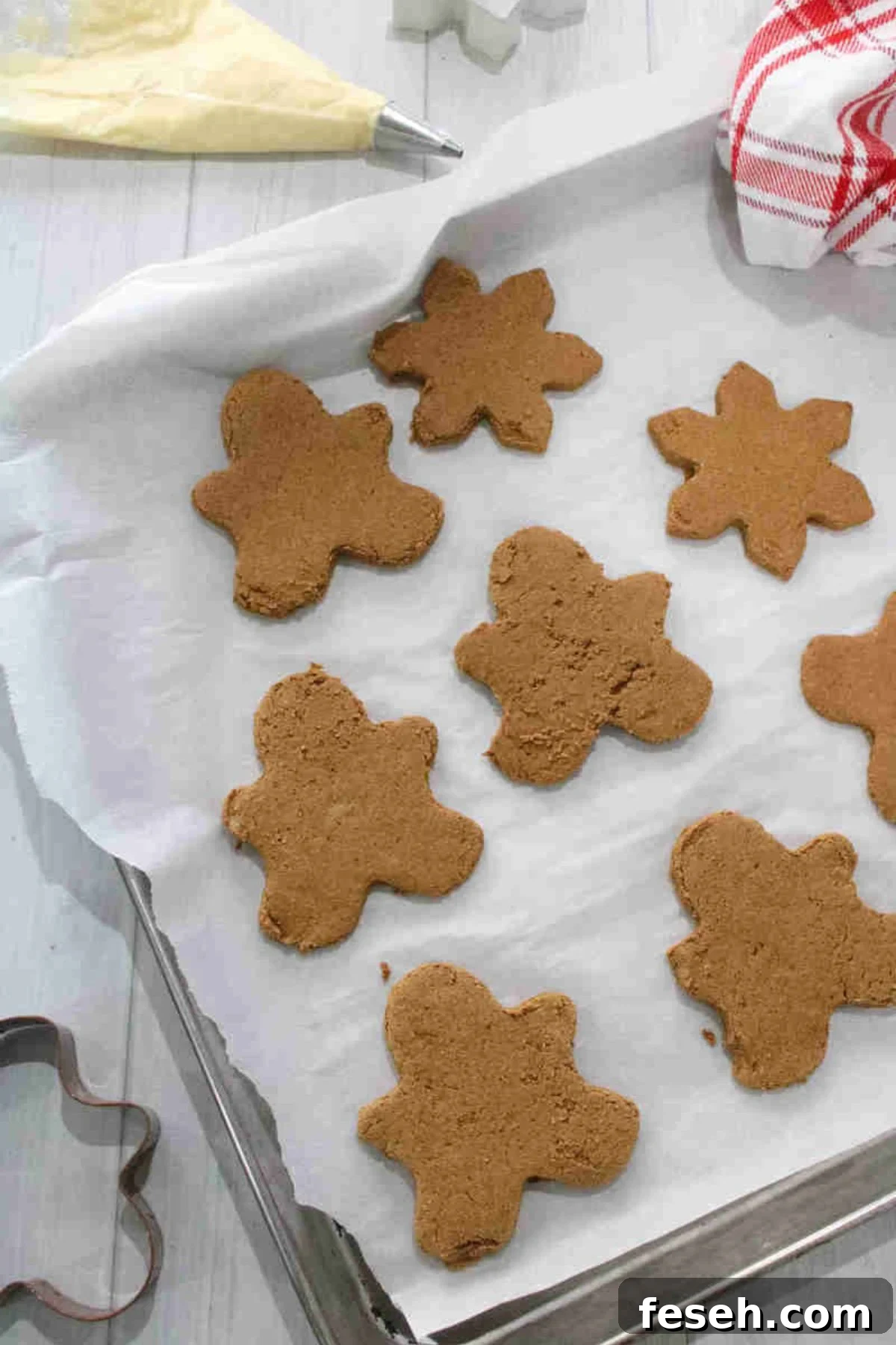 Raw gingerbread cookies cut out on a baking pan lined with parchment paper.