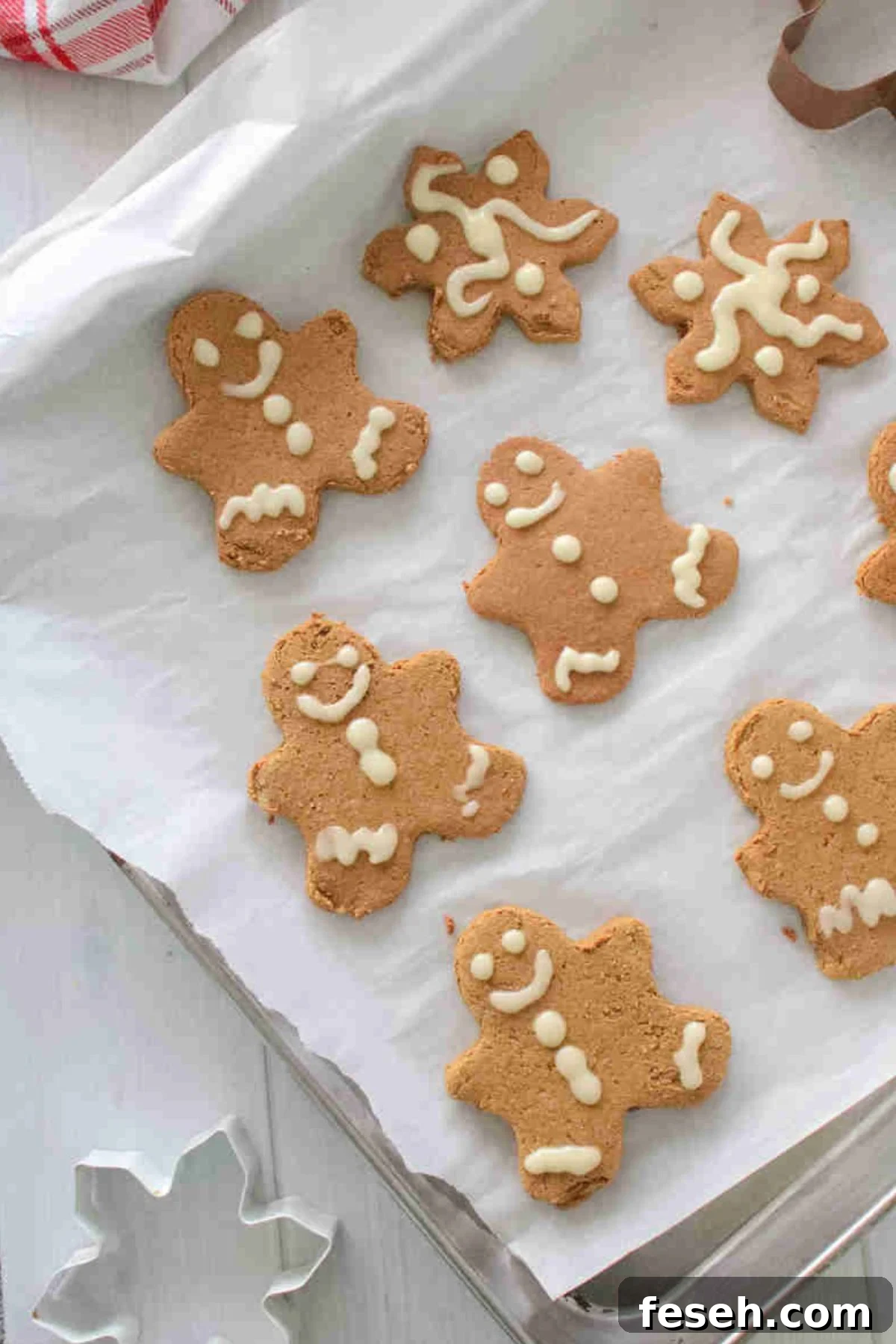Decorated gingerbread cookies on a parchment paper-lined baking sheet.