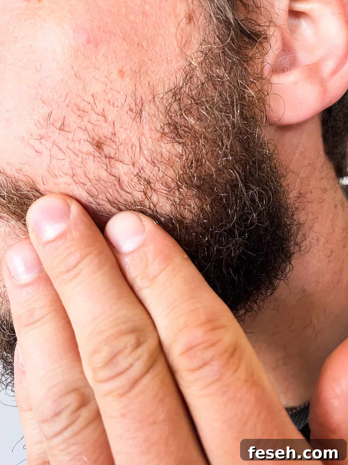 Rubbing beard oil into a beard.