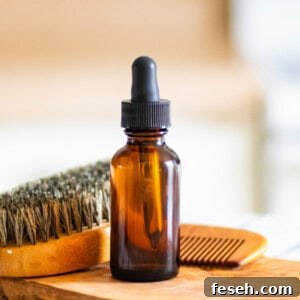 A bottle of homemade beard oil with a beard brush on a wooden board.