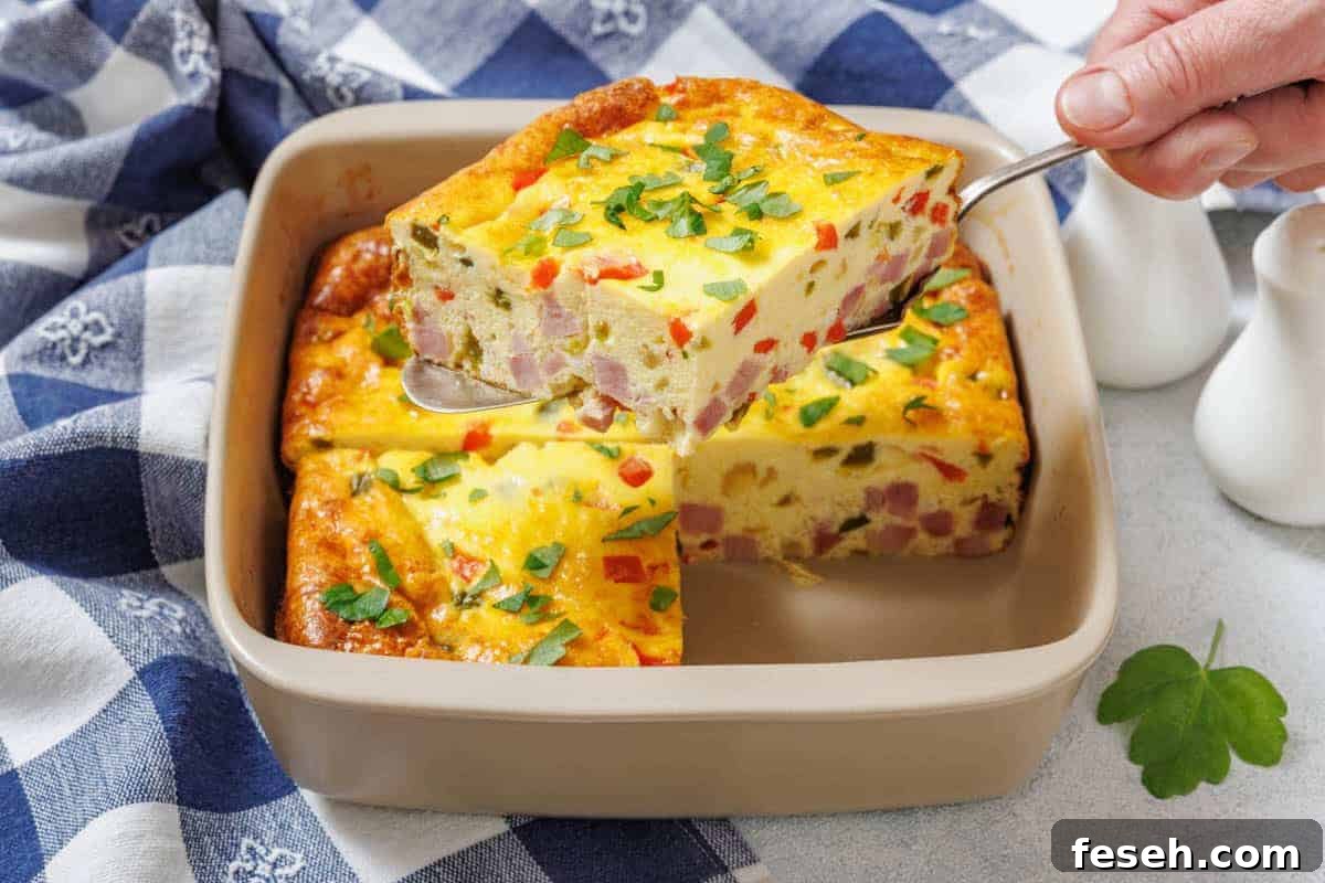 17 Pantry-Friendly Nanna Casseroles That Taste Homemade and Luxurious 9 A hand holds a spatula lifting one piece of Grandma’s Baked Western Omelet from a square dish.