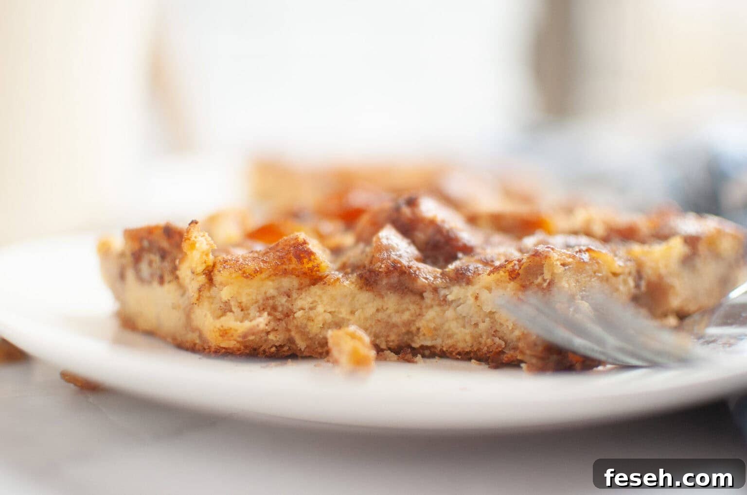 17 Pantry-Friendly Nanna Casseroles That Taste Homemade and Luxurious 10 A close-up of a partially eaten piece of Cinnamon Roll Casserole on a white plate, with a fork resting beside it.