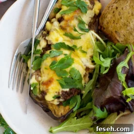An overhead of a white dish of Greek stuffed eggplant or papoutsakia with a knife and fork