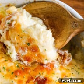 A wooden spoon is being used to scoop out a casserole full of broccoli and cauliflower.