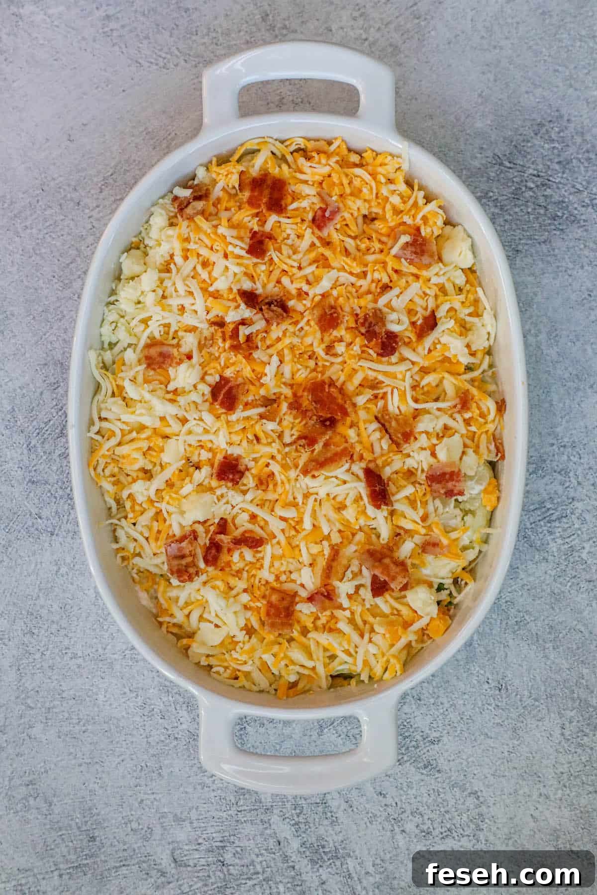 A broccoli and cauliflower casserole dish topped with cheese and bacon.