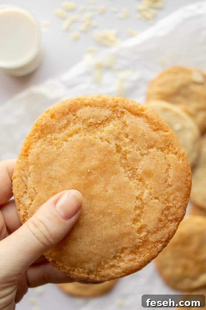 A hand holding a golden cookie with others in the background.