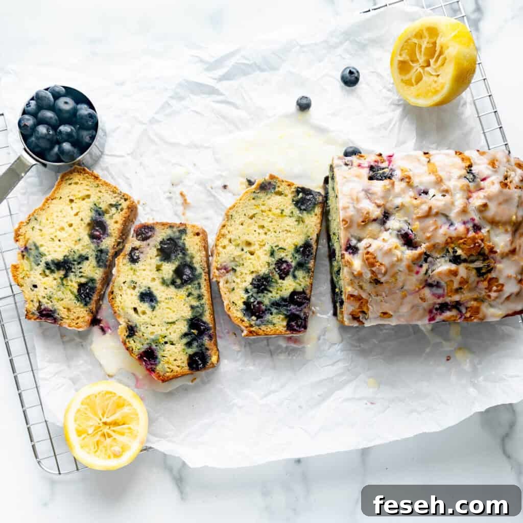 Blueberry Zucchini Bread on white parchment paper with lemon and blueberries around it.