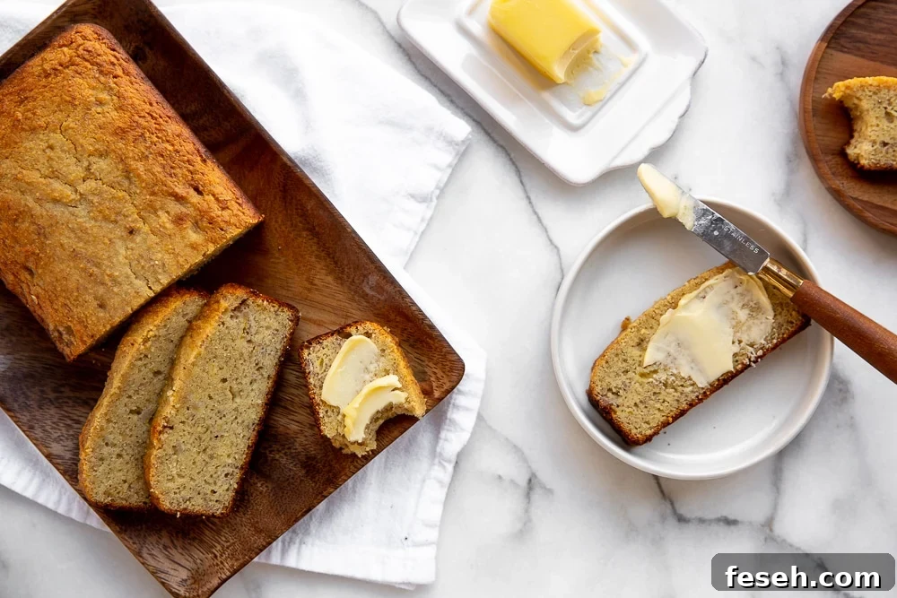 Overhead shot of paleo banana bread on board with buttered slice on plate