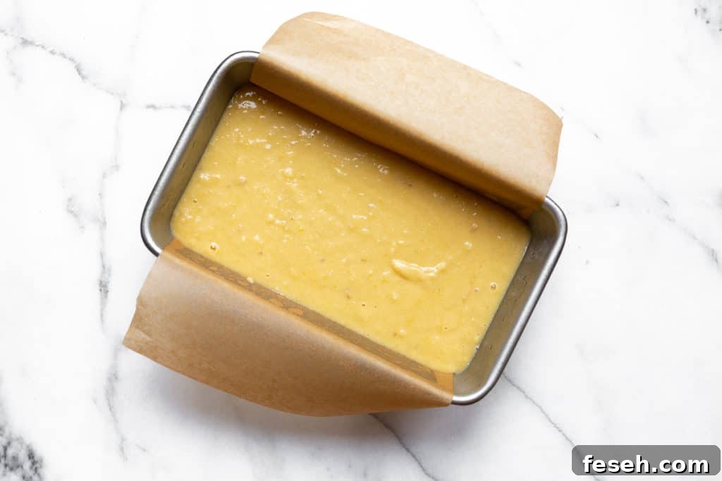 The banana bread batter in a parchment lined loaf pan.