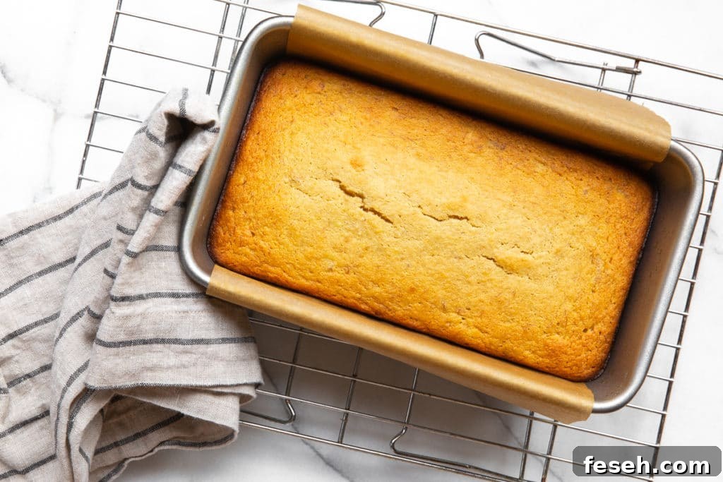 The baked banana bread in the pan on a cooling rack.