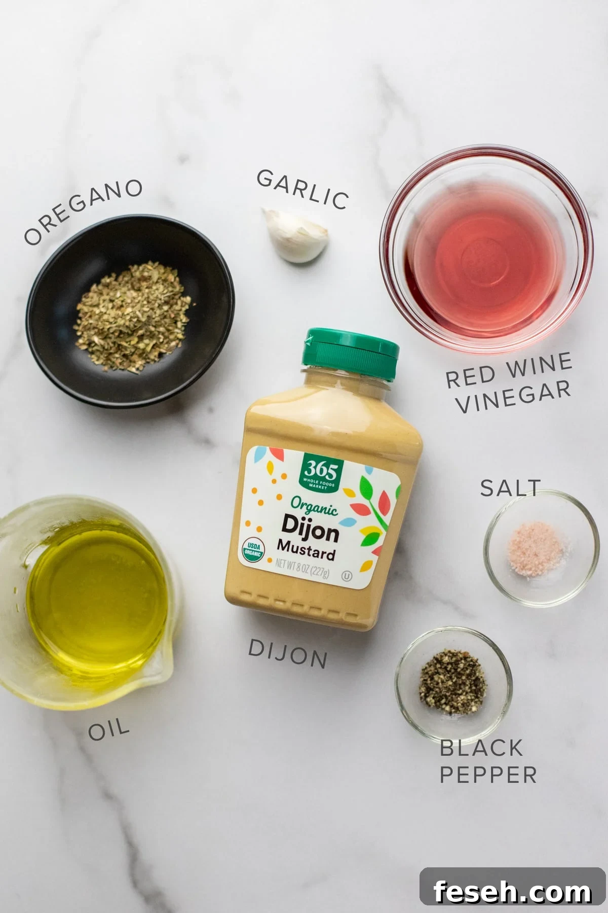 Ingredients for greek dressing arranged on a white counter.