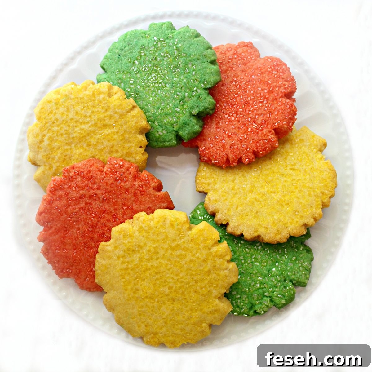 Yellow, green, orange Mexican Sugar Cookies in a circle on a white plate.