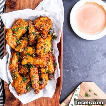 Overhead shot of baked wings in wooden bowl on blue counter.
