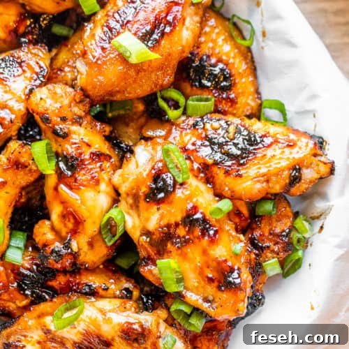 Peach wings in a white bowl on a white counter.