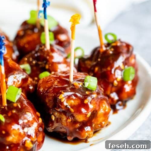 Meatballs on a white plate with toothpicks in them.