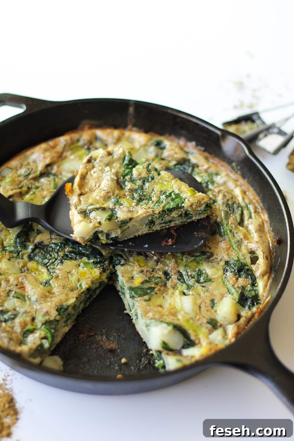 Potato Leek Frittata in a cast iron skillet with a slice taken out.