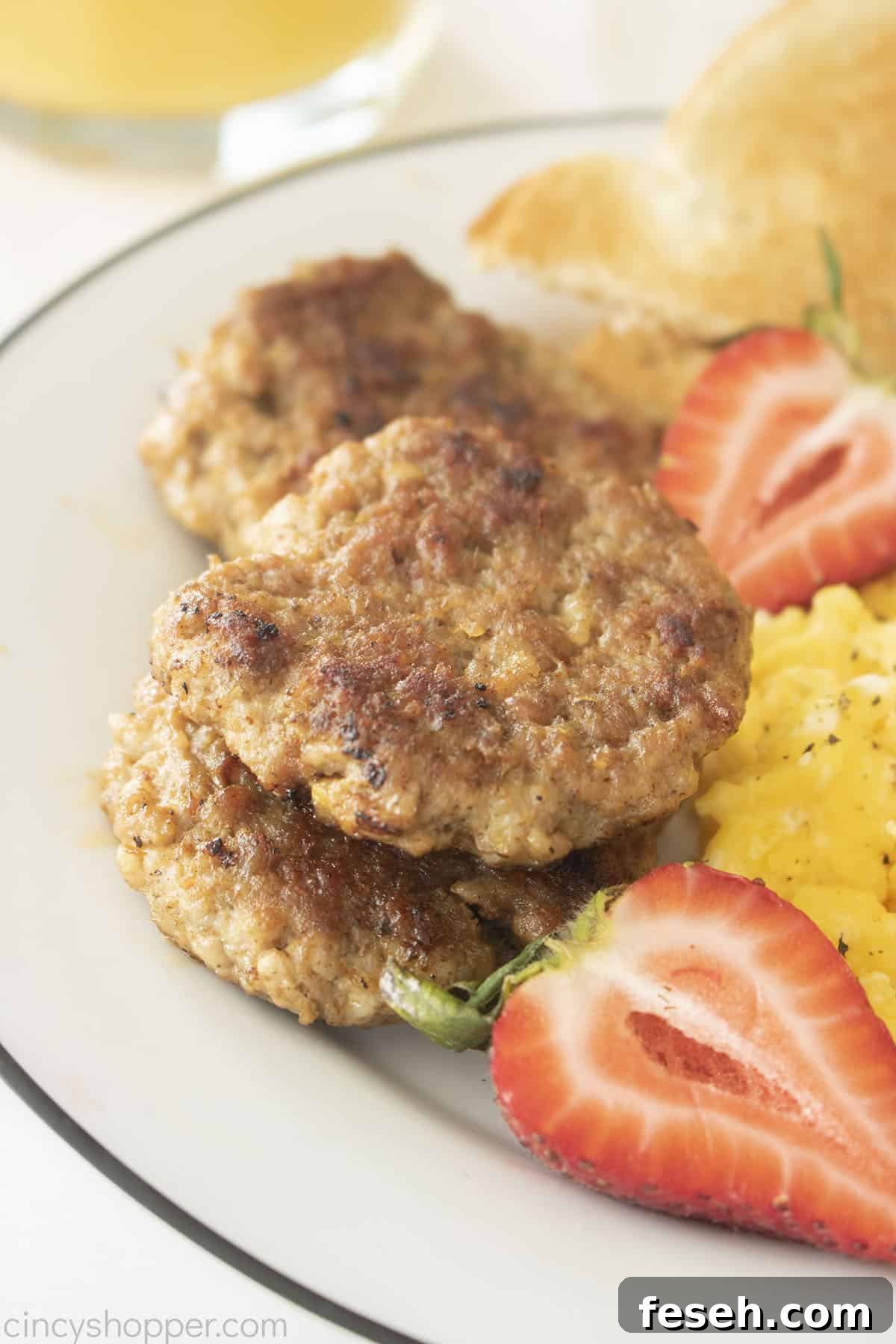 Homemade Breakfast Sausage Patties on a white plate with eggs and strawberries.