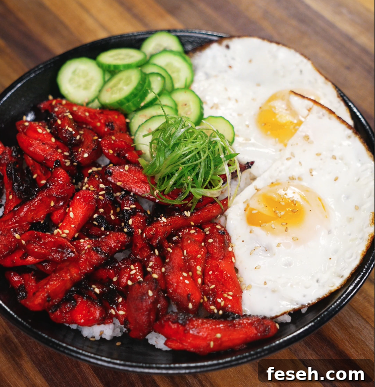 The finished Chicken Tocino bowl served with sunny-side-up eggs, sliced cucumbers, and scallions over white rice. The sweet and savory glazed chicken is caramelized perfectly, offering a classic Filipino breakfast presentation.