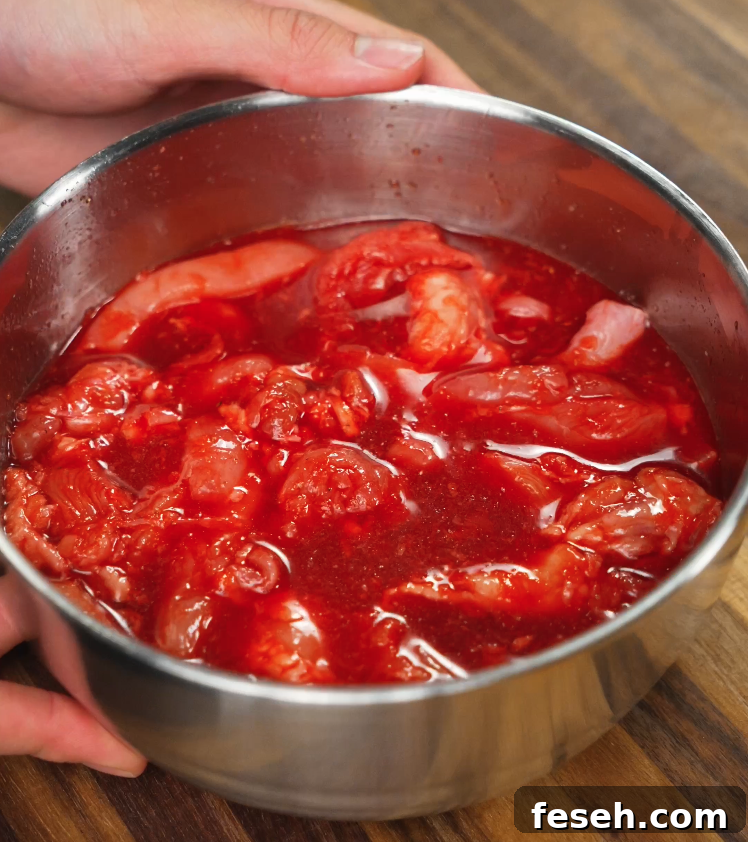 Raw chicken thighs fully coated in a vivid red marinade made with annatto powder, sugar, garlic, and pineapple juice. This step is crucial for flavor absorption and achieving the iconic red tocino color.