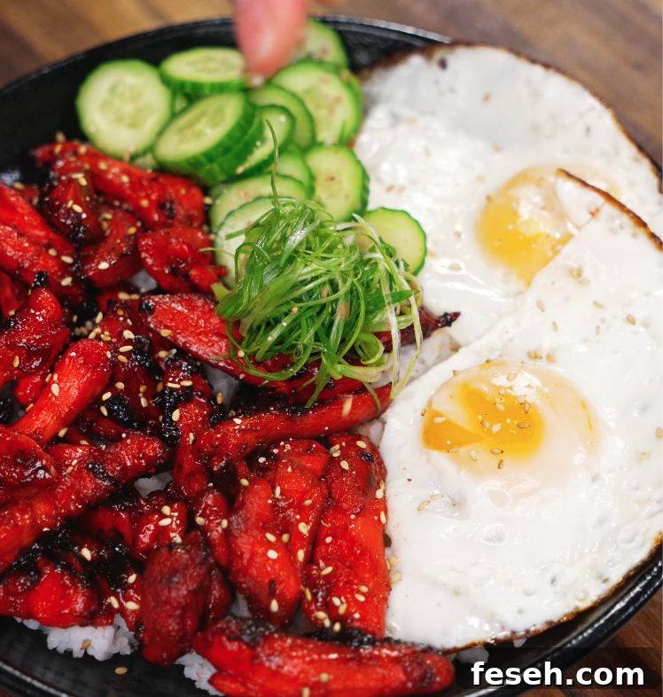 Garnishing the finished Chicken Tocino bowl with thinly sliced scallions and crisp cucumbers. The vibrant toppings add freshness and crunch to the rich, savory meal.