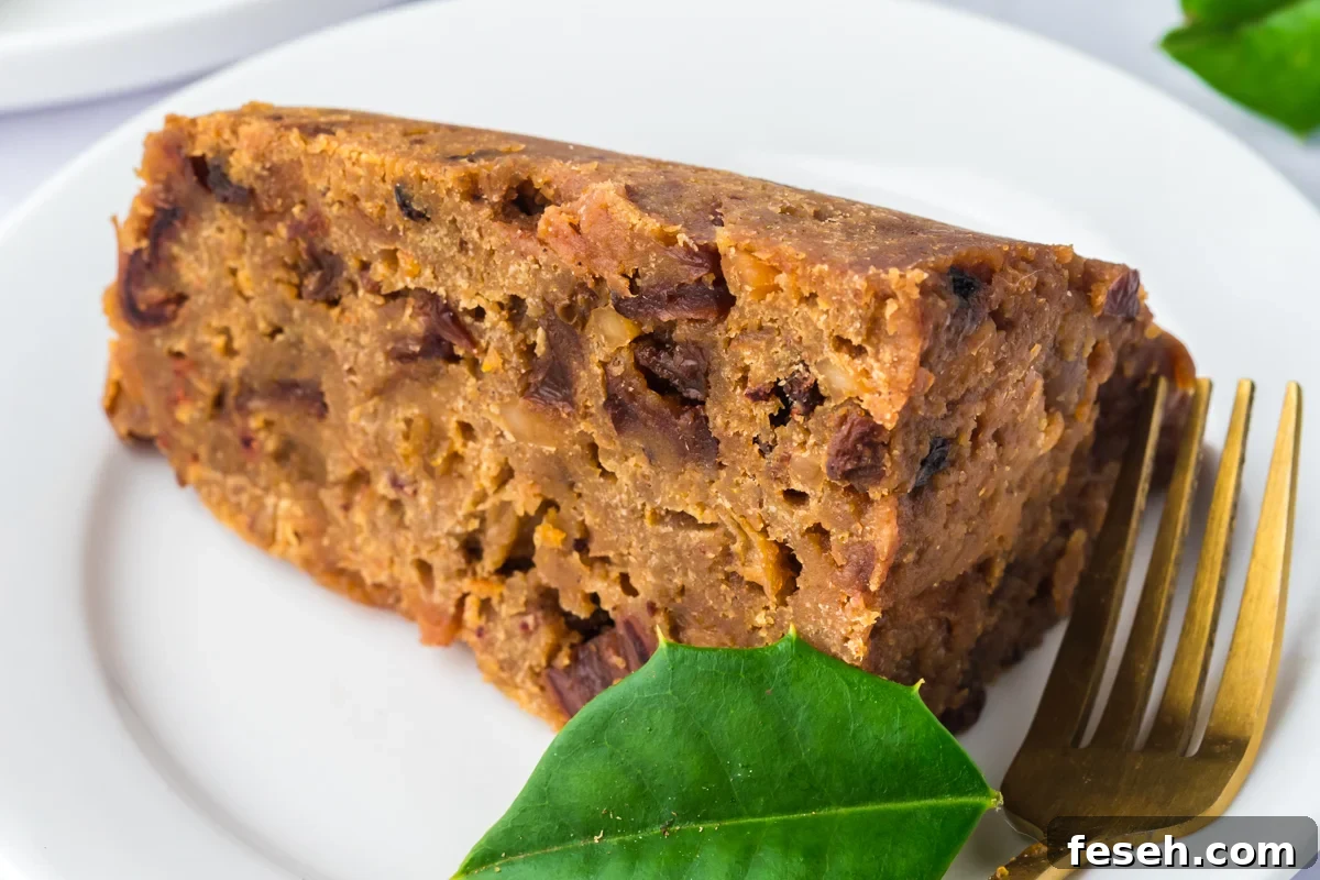Close-up of a slice of slow cooker figgy pudding on a plate with a fork.