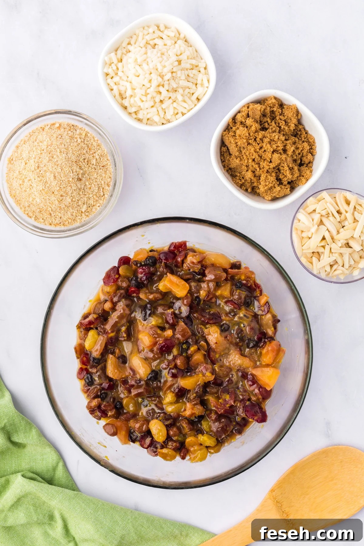 Eggs and almond extract added to rehydrated dried fruits in a bowl.