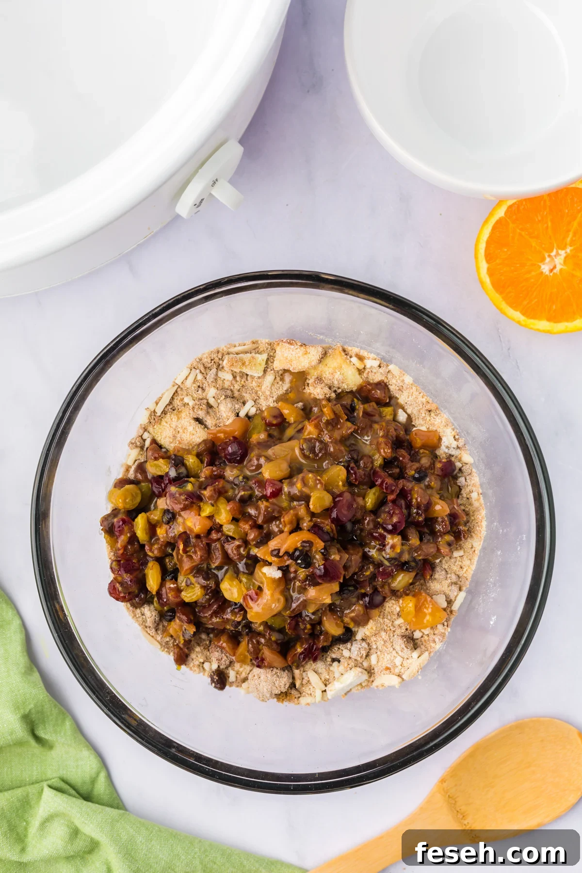 Fruit mixture added to dry ingredient mixture in a glass bowl.