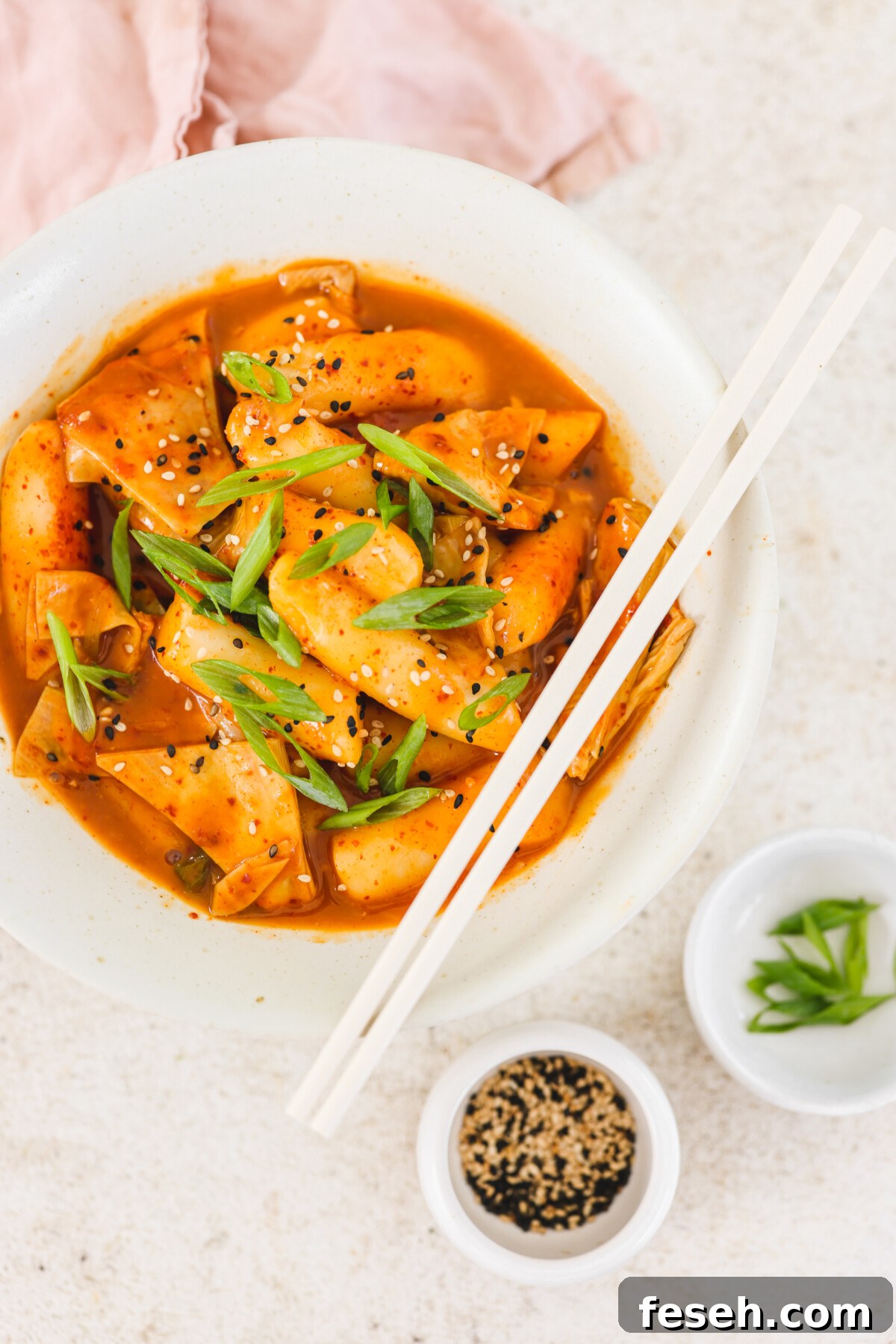 a white bowl filled with vegan tteokbokki with chopsticks resting on the side of the bowl