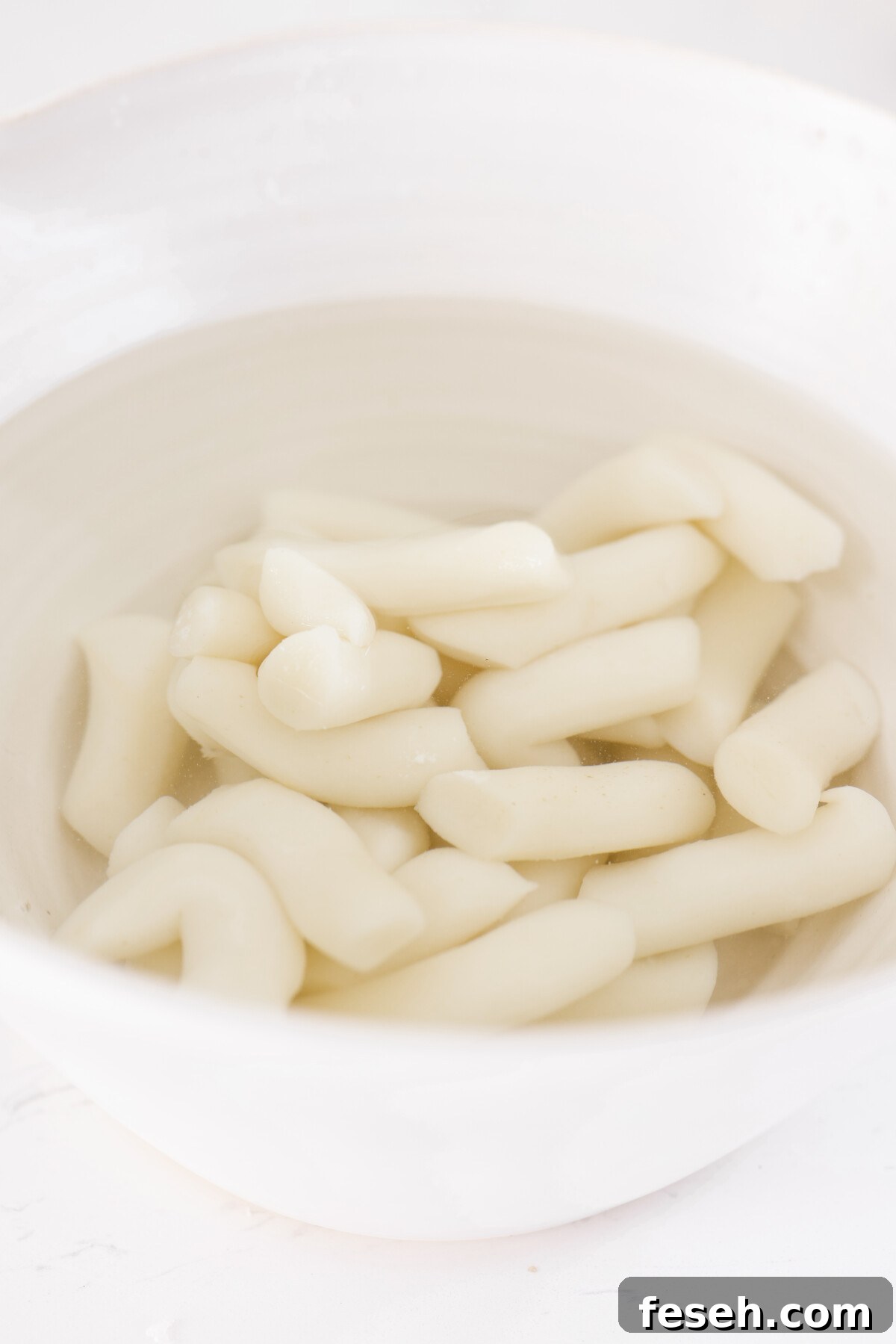 korean rice cakes sitting in a bowl of water