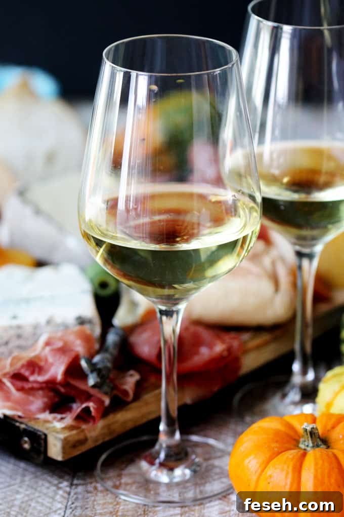 Two glasses with Italian white wine and meat with cheese board