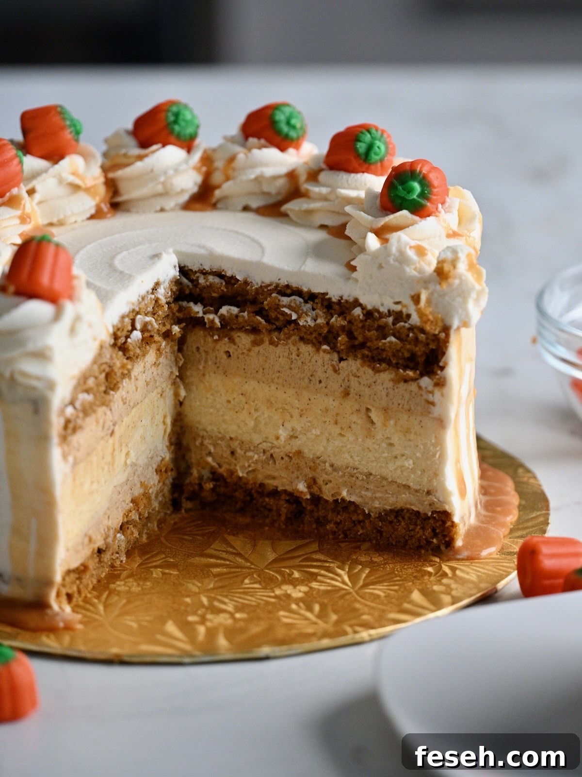 Pumpkin cake cheesecake with layers of pumpkin cake, cheesecake, and pumpkin mousse, topped with whipped cream.