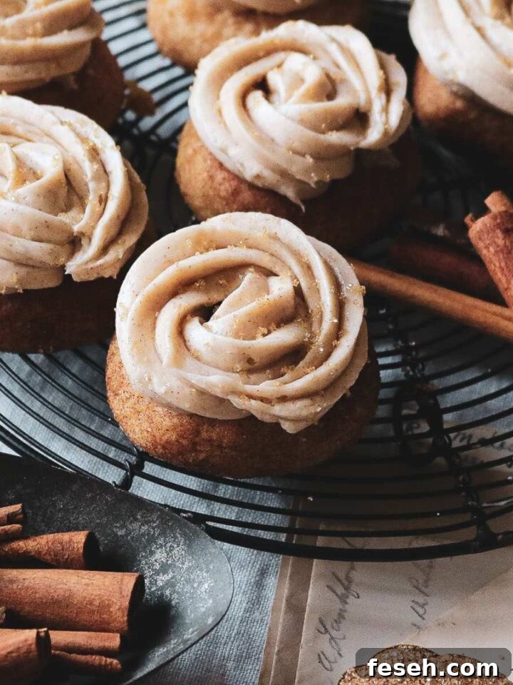 close up view of frosted snickerdoodles on a wire rack next to cinnamon sticks.