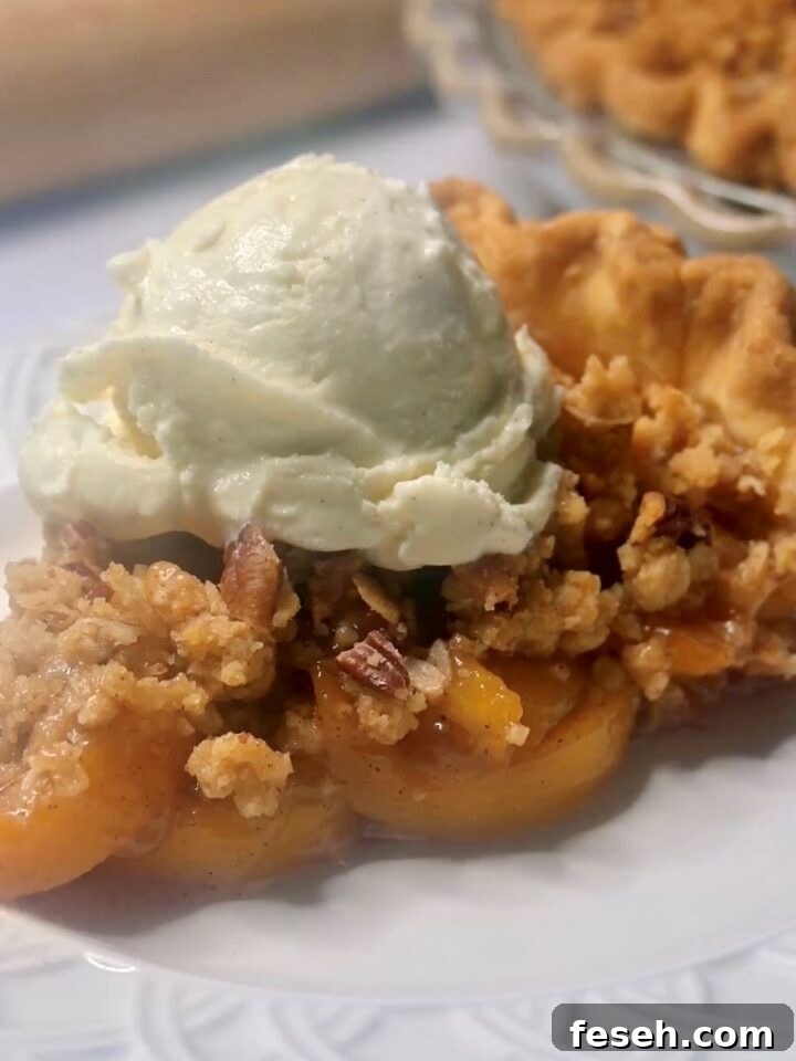 A slice of peach pie with a crumble topping on a plate.