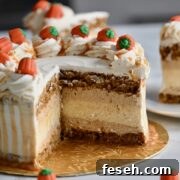A close-up of a festive pumpkin cake cheesecake layer cake decorated with caramel-drizzled whipped cream swirls and candy pumpkins on top.