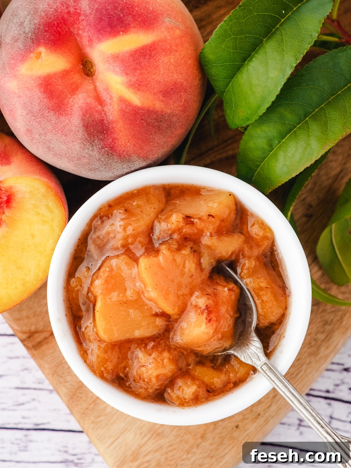 Compote in serving bowl with spoon and fresh peaches.