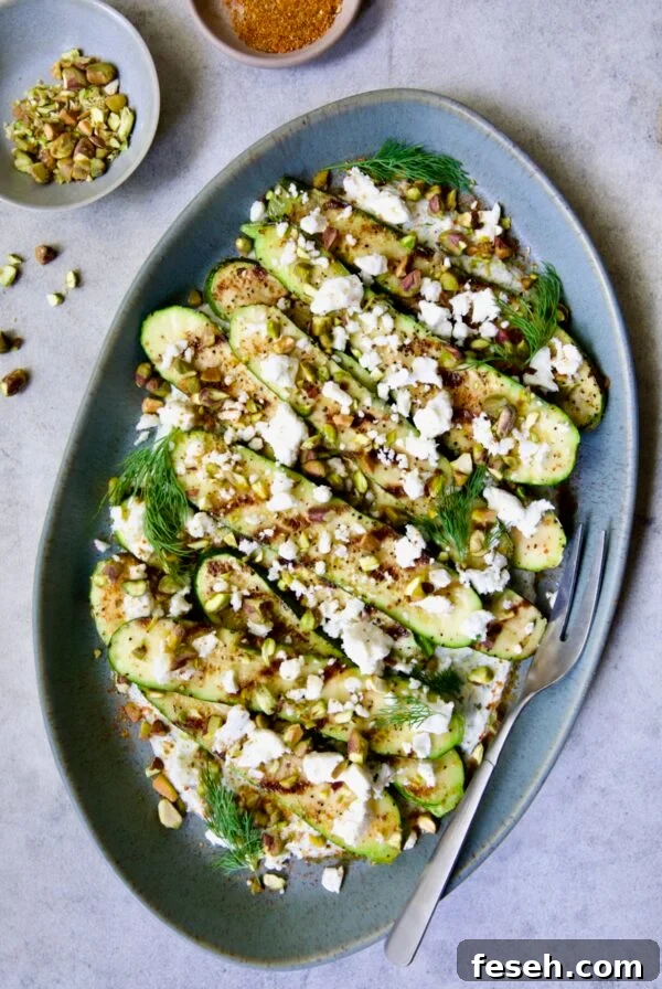 Mediterranean Grilled Zucchini with Dill Yogurt and Feta on blue platter garnished with pistachios and fresh dill sprigs.