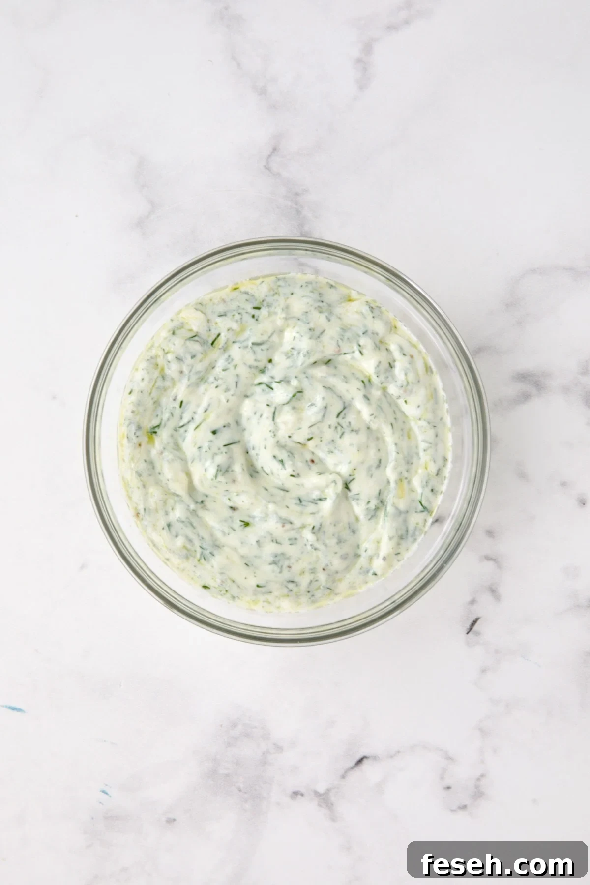 Dill yogurt in glass bowl.