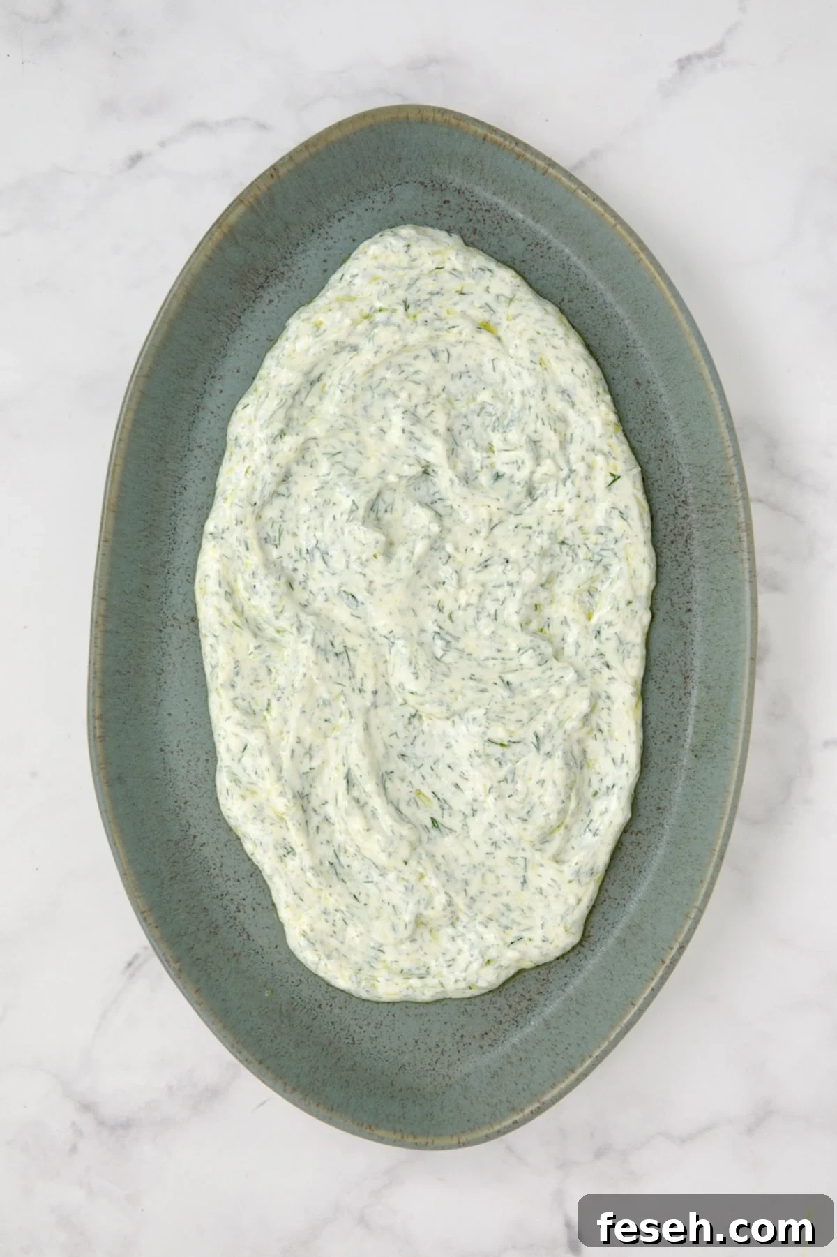 Dill yogurt spread out on blue platter.