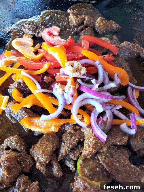 Blackstone steak fajitas cooking on blackstone griddle with vegetables